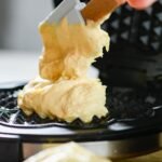 Delicious waffle batter being spread on a waffle maker for a tasty breakfast.